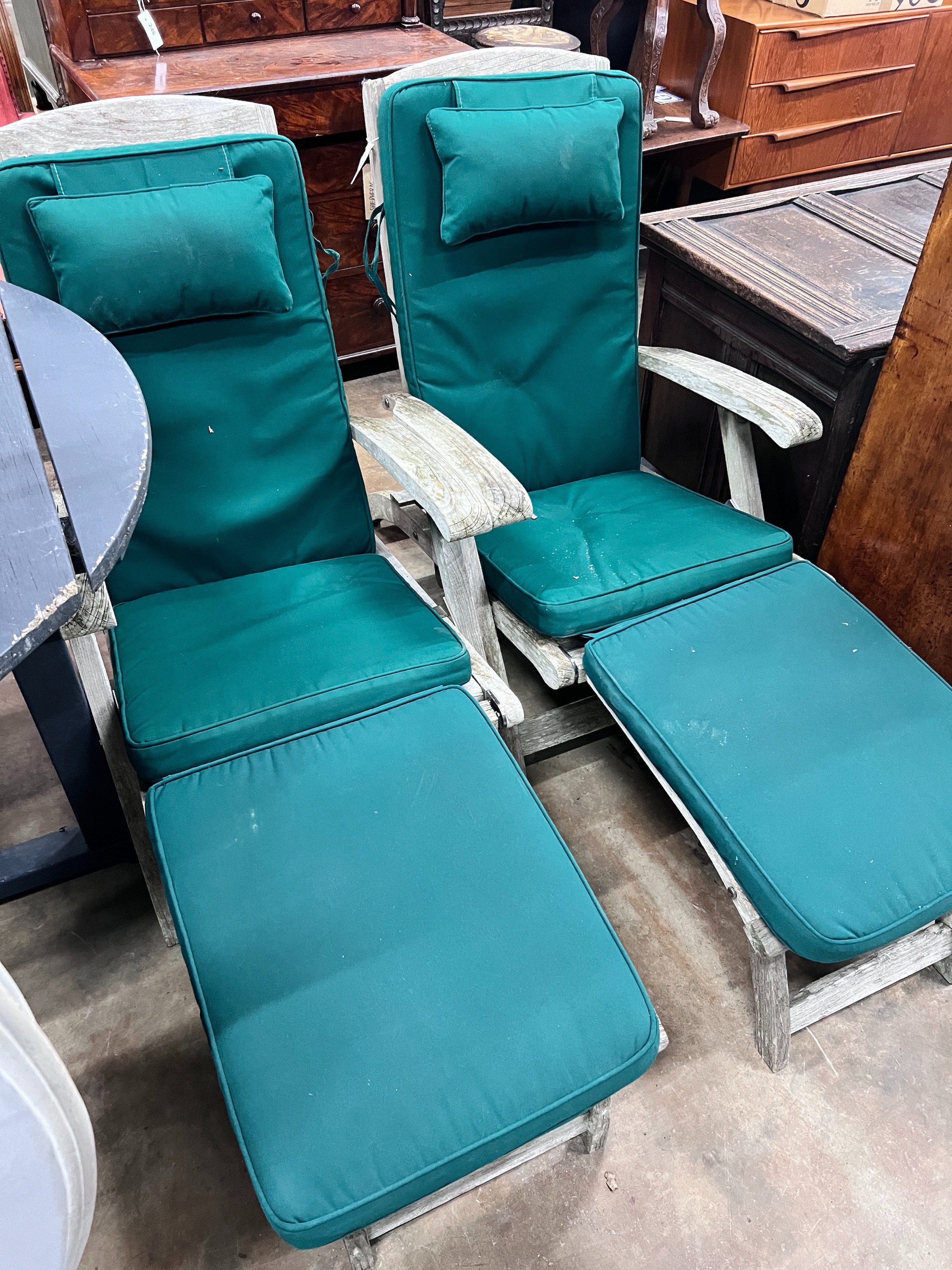 A pair of Indian Ocean weathered teak Burnham steamer chairs with green fabric squab cushions